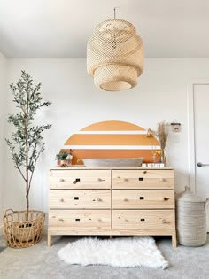 a bedroom with a dresser, bed and potted plant in the corner next to it