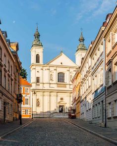 an empty cobblestone street in front of old buildings with steeple tops on either side