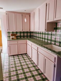 a kitchen with pink cabinets and green checkered flooring on the tile counter tops