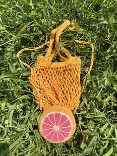 a small bag with a grapefruit cut in half sitting on the green grass