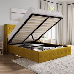 a bed with a yellow frame and mattress in a room next to a white rug