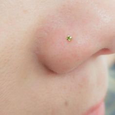 a woman's nose with a tiny green jewel on it, and the tip of her nose is visible