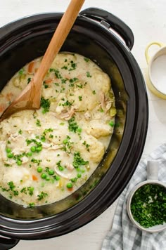 a crock pot filled with chicken and dumplings next to a cup of tea