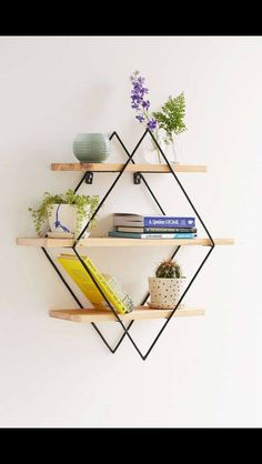 three shelves with books and plants on them against a white wall, one shelf has a yellow book