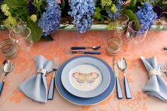 the table is set with blue and pink flowers