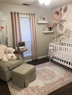 a baby's room with a white crib and pink flowers on the wall