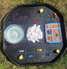 a child's chalk board with various items on it sitting in the middle of grass