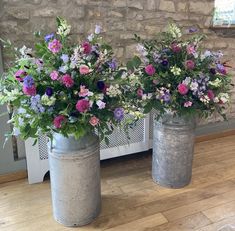 two metal buckets with flowers in them sitting on the floor next to a radiator