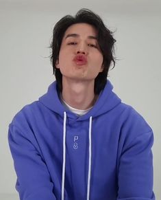 a young man making a funny face with his tongue sticking out and wearing a blue hoodie