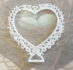 a white heart shaped brooch sitting on top of a piece of paper