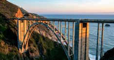 a large bridge spanning over the ocean on top of a cliff next to the ocean