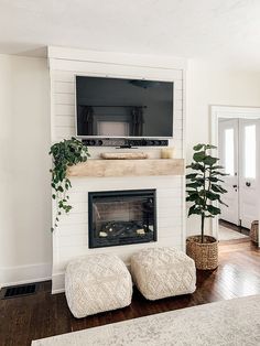 a living room with a fireplace, television and ottomans