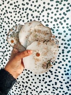 a person holding something in their hand on top of a polka dot wallpapered surface