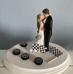 a bride and groom figurine on top of a cake with checkered flags