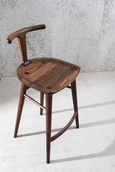 a wooden chair sitting on top of a white floor next to a cement wall with a hole in it