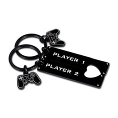 two black key chains with video game controllers on them, one has a player 1 and the other is a controller 2