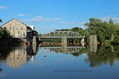 a bridge over a body of water with buildings in the background and trees on either side