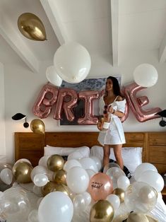 a woman standing on a bed surrounded by white and gold balloons that spell out the word bride