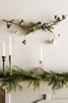 a mantel with candles and greenery on it, hanging from the wall next to a fireplace