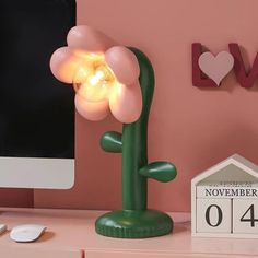 a desk with a computer and a flower lamp on top of the desk next to it