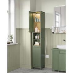 a bathroom with a green cabinet next to a white sink and window in the corner