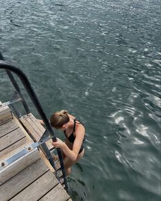 a woman in a black bathing suit climbing into the water