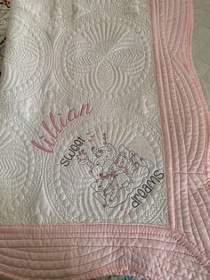 a pink and white quilted bed with the name william written in cursive writing on it