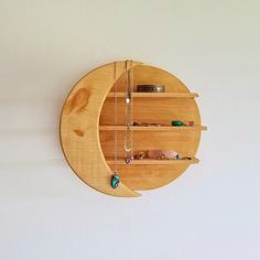 a circular wooden shelf with necklaces and jewelry hanging from it's sides on a white wall