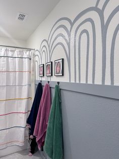 three towels hanging on the wall next to a shower curtain and two framed pictures above it