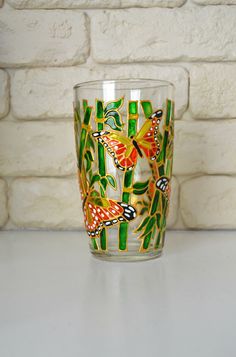 a glass sitting on top of a counter next to a brick wall with butterflies painted on it