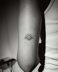 a woman's arm with a small sun tattoo on the left side of her body