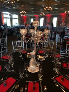 a black table topped with lots of silverware next to tall chandelier lamps