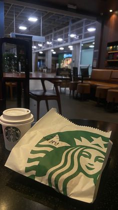 a starbucks bag sitting on top of a table next to a cup of coffee in a restaurant