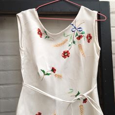 "Pretty handmade vintage dress.  Lovely floral embroidery on linen or maybe cotton fabric. Ties up at the front . Good clean condition. I think the dress is 50s bit the embroidery looks older and the zip is plastic. Roughly size small to medium. Measured flat Pit to pit 18\" Waist 16\" Pit to hem 28.5\"" Vintage Cotton Dress With Floral Embroidery, Vintage Cotton Embroidered Dress With Floral Embroidery, Retro Embroidered Cotton Dress, Fitted Vintage Embroidered Dress With Floral Embroidery, Spring Vintage Cotton Embroidered Dress, Vintage Cotton Embroidered Dress For Spring, Vintage Floral Embroidery Dress For Garden Party, Vintage Embroidered Sleeveless Dress, Vintage Sleeveless Embroidered Dress