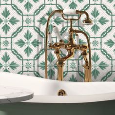 a bathtub with two faucets in front of a green and white tiled wall