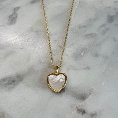 Heart necklace with white stone. It is 17 inches long and made of brass dipped in 18k gold. We ship across the US! White Plated Pendant Necklaces, White Plated Pendant Necklace, Dainty Heart-shaped Brass Necklaces, White Plated Necklaces As Gift, White Clavicle Chain Necklace With Open Heart, White Open Heart Clavicle Chain Necklace, Gold Plated Heart Shaped Pearl Pendant Necklace, White Heart Cut Necklace For Gift, Gold Heart Necklace With Pearl Pendant For Gift