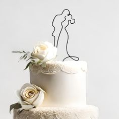 a white wedding cake decorated with flowers and an image of a kissing couple on top