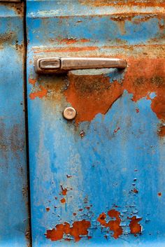 an old rusted blue door with a metal handle