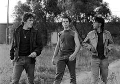 three young men walking down a dirt road