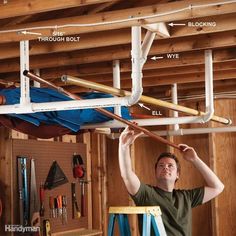 a man is working on the ceiling in his garage, with tools and equipment attached to it