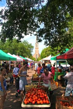 people shopping at an outdoor farmers market with lots of fruit and vegetables on the tables