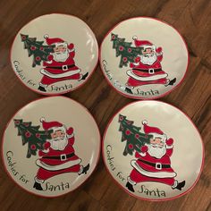 four santa claus plates with christmas tree on the front and bottom, sitting on a wooden floor