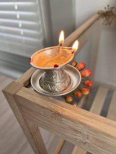 a small metal candle holder sitting on top of a wooden table