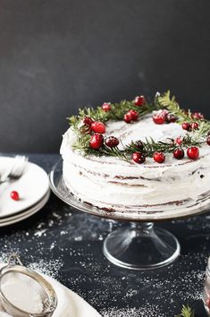 a cake with white frosting and cranberries on top sitting on a table