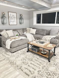 a living room with gray couches and white rugs on the floor in front of a large window