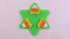 an ornament made out of legos on a white surface with green and orange beads