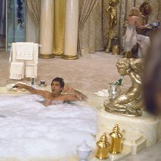 a man laying on the floor in a bathtub surrounded by gold statues and candles