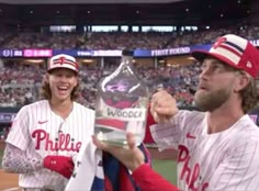 two baseball players holding trophies in front of a crowd