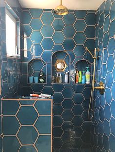 a blue tiled shower with shelves on the wall