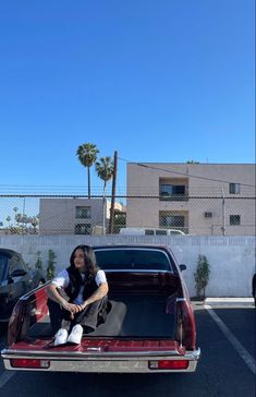 a woman sitting on the back of a car in a parking lot